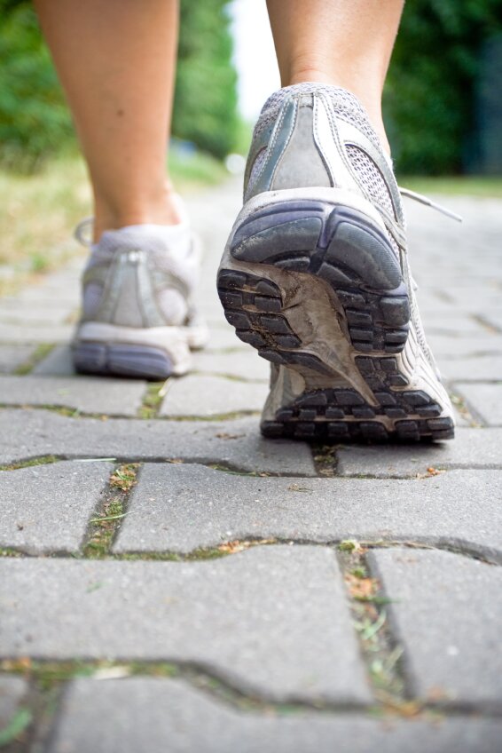Woman walking on sidewalk, sport shoe close-up